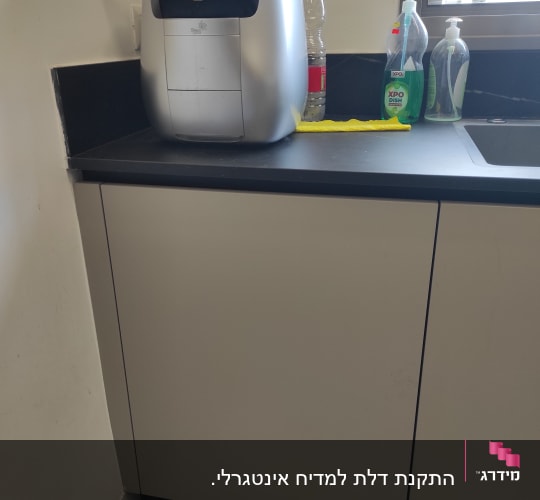 מכונת קפה על משטח מטבח עם חומרי ניקוי